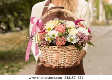Girl florist holding basket of flowers her hands.flower composition.Floristry courses.photography with fresh flowers. sale of flowers flower shop.big basket with roses