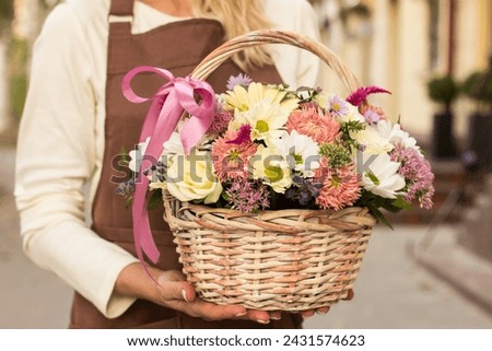 Girl florist holding basket of flowers her hands.flower composition.Floristry courses.photography with fresh flowers. sale of flowers flower shop.big basket with roses Royalty-Free Stock Photo #2431574623