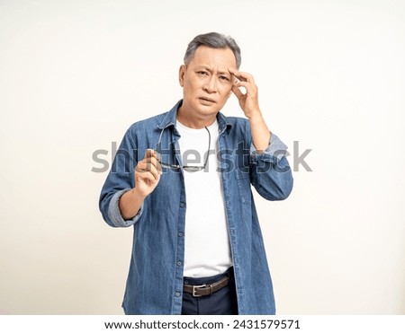 Handsome asian mature old man standing headache hands rubbing eye on isolated white background. Portrait of serious depressed senior asian man eye pain. Mature People and lifestyle Royalty-Free Stock Photo #2431579571