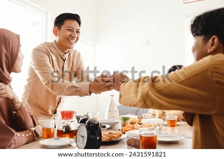 Young moslem men handshaking while meeting at breakfasting moment  in Ramadan Royalty-Free Stock Photo #2431591821