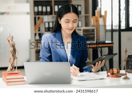 justice and law concept. asian woman lawyer working and judge in a courtroom the gavel, working with tablet and laptop and digital tablet computer on white table 
