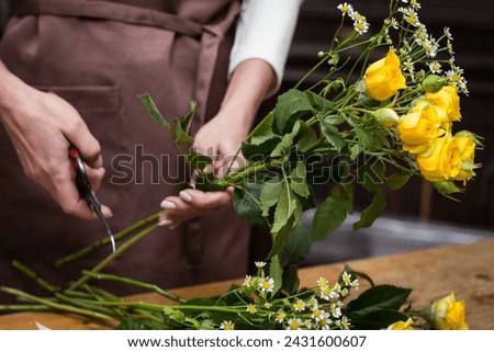 Girl florist makes bouquet.Flowers close-up the hands of florist.Florist cuts rose flowers with secateurs.pruning stems with secateurs.girl cut flowers with secateurs close-up. floristry courses. Royalty-Free Stock Photo #2431600607
