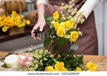 Girl florist makes bouquet.Flowers close-up the hands of florist.Florist cuts rose flowers with secateurs.pruning stems with secateurs.girl cut flowers with secateurs close-up. floristry courses Royalty-Free Stock Photo #2431600649