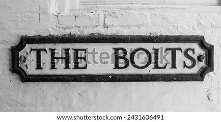 Old road sign Road Sign on a yellow brick wall giving its location as "The Bolts."