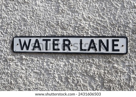 Old road sign Road Sign on a yellow brick wall giving its location as "Water Lane."