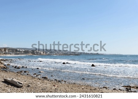 Sea stone beach, blue sea, on the distant horizon a coastal town against the backdrop of mountains