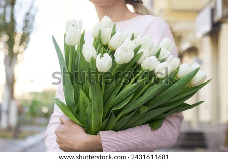 girl holding white tulips close-up.girl with tulips on the street.floristry courses Royalty-Free Stock Photo #2431611681