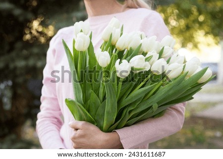 girl holding white tulips close-up.girl with tulips on the street.floristry courses Royalty-Free Stock Photo #2431611687