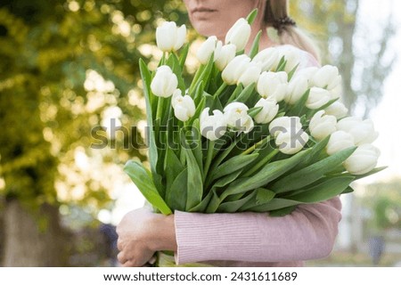 girl holding white tulips close-up.girl with tulips on the street.floristry courses Royalty-Free Stock Photo #2431611689