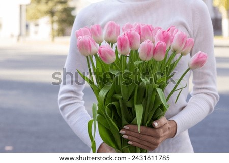 girl holding pink tulips close-up.girl with tulips on the street.floristry courses Royalty-Free Stock Photo #2431611785