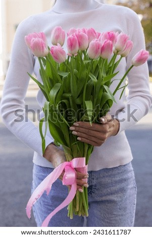 girl holding pink tulips close-up.girl with tulips on the street.floristry courses Royalty-Free Stock Photo #2431611787