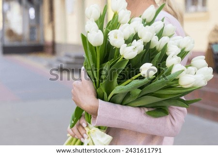 girl holding white tulips close-up.girl with tulips on the street.floristry courses Royalty-Free Stock Photo #2431611791