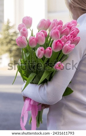 girl holding pink tulips close-up.girl with tulips on the street.floristry courses Royalty-Free Stock Photo #2431611793