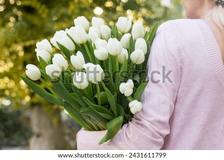 girl holding white tulips close-up.girl with tulips on the street.floristry courses Royalty-Free Stock Photo #2431611799