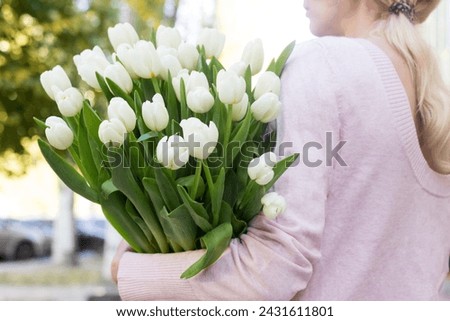 girl holding white tulips close-up.girl with tulips on the street.floristry courses Royalty-Free Stock Photo #2431611801