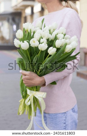 girl holding white tulips close-up.girl with tulips on the street.floristry courses Royalty-Free Stock Photo #2431611803