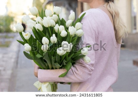 girl holding white tulips close-up.girl with tulips on the street.floristry courses Royalty-Free Stock Photo #2431611805
