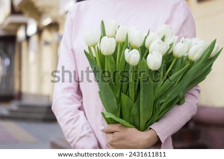 girl holding white tulips close-up.girl with tulips on the street.floristry courses Royalty-Free Stock Photo #2431611811