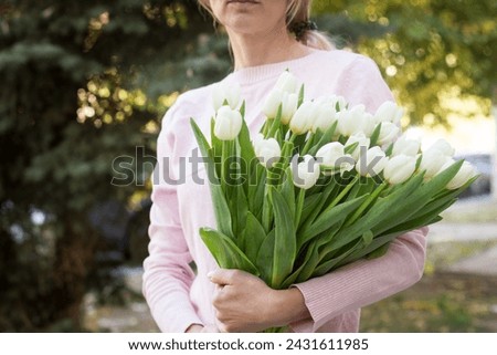 girl holding white tulips close-up.girl with tulips on the street.floristry courses Royalty-Free Stock Photo #2431611985