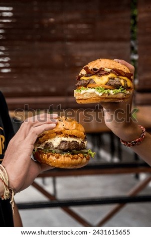 two friends holding a cheeseburger in each hand