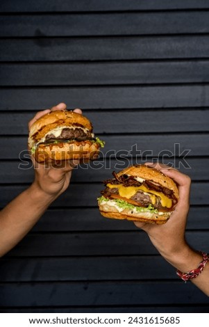 two friends eating cheeseburgers in front of a garage