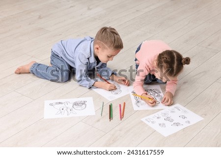 Cute little children coloring drawings on warm floor indoors. Heating system