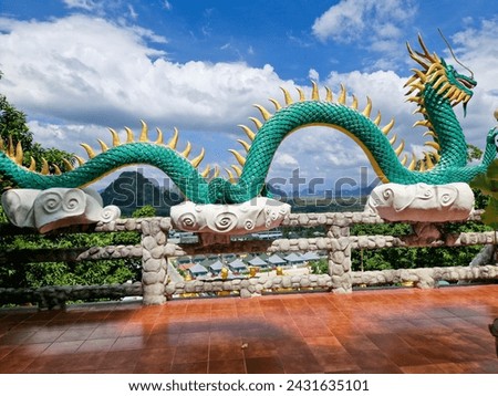 Big green dragon with golden pieces. Behind the chinese dragon is mountain. Picture taken during sunny day.