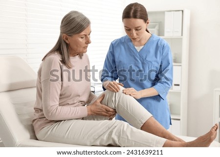 Arthritis symptoms. Doctor examining patient with knee pain in hospital Royalty-Free Stock Photo #2431639211