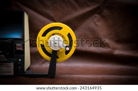 A vintage 8mm movie editing desktop with editing machine part and yellow reel on colored background
