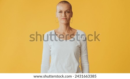 Hairless young woman looking at camera isolated on yellow background in studio