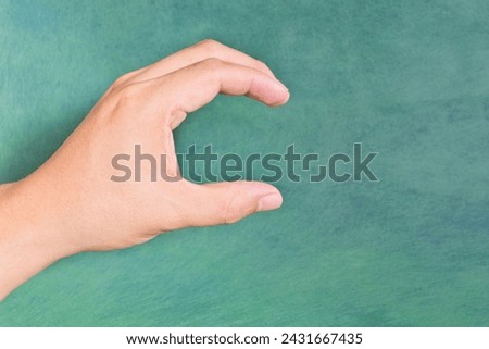 Young male Asian hand making letter C sign isolated on green background.