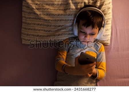 Face of kid, headphones and tablet for reading eBook, watch movies and play video game on eLearning app. Happy boy child, digital tech and listening to multimedia, music and streaming cartoon at night