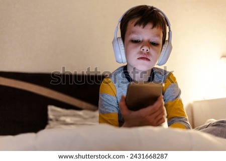 Face of kid, headphones and tablet for reading eBook, watch movies and play video game on eLearning app. Happy boy child, digital tech and listening to multimedia, music and streaming cartoon at night