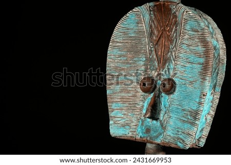 Close up of a wooden Kota reliquary figure from Gabon, isolated on a black background. Tribal African art, showcasing masterful craftsmanship and spiritual symbolism. Royalty-Free Stock Photo #2431669953