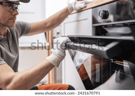 Caucasian Technician Installing and Testing Brand New Kitchen Stove Royalty-Free Stock Photo #2431670791