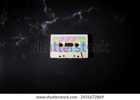 Top view a music cassette with colorful retro label on black background.