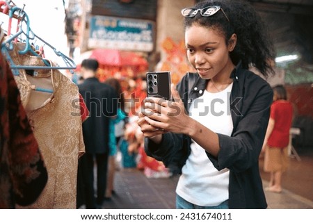 Asian woman enjoy travel in  downtown district and she taking a photo and using mobile live on social media and tasting streetfoods.