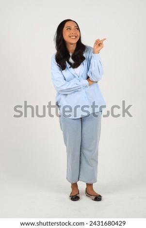 Young elegant beautiful Asian woman smiling and pointing to empty copy space isolated on white background