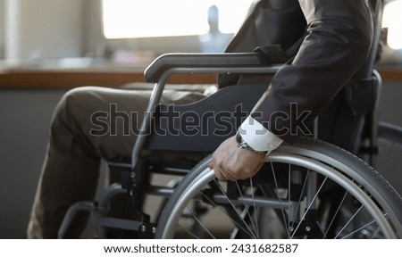 Close-up of disabled man on wheelchair in office wearing presentable suit. Adaptation of people with disabilities in society. Recovery and healthcare concept Royalty-Free Stock Photo #2431682587
