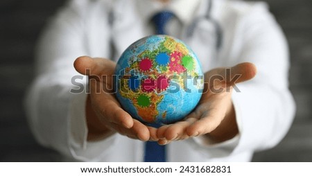 Close-up of person holding small globe in hands. Male in presentable suit. Extension of microbes and disease. Germs on world map. Infection and spread of virus concept Royalty-Free Stock Photo #2431682831
