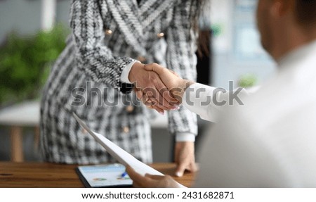 Close-up of business partners shaking hands. Young woman in presentable luxury suit holding document. Signing contract and make deal. Finance and economy concept Royalty-Free Stock Photo #2431682871