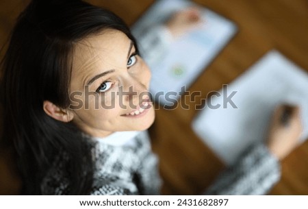Top view of smiling female signing contract in office. Happy brunette company worker in presentable suit. Copy space in right side. Business and finance concept Royalty-Free Stock Photo #2431682897