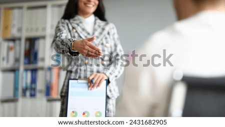 Close-up of cheerful employee extend hand for handshaking. Woman in luxury presentable suit. Clipboard with important diagram paper. Company and co-workers concept Royalty-Free Stock Photo #2431682905