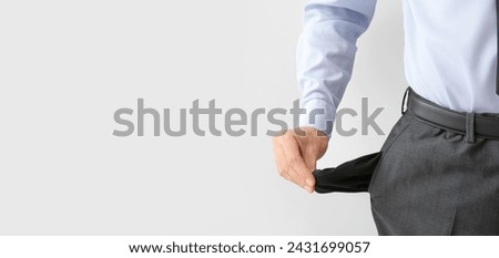 Businessman with empty pockets on light background with space for text. Bankruptcy concept