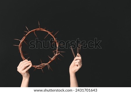 Female hands with crown of thorns and nails on dark background. Good Friday concept