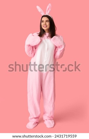 Happy young woman in bunny costume on pink background. Easter celebration