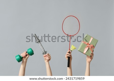 Female hands with sports equipment and gift box for International Women's Day on grey background
