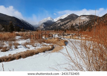 Snow in varying degrees in the high country in the Colorado Rockies.  Trees and snow in the foreground of the Mountains of Colorado.  Pockets of snow and drifts surrounded by dormant vegetation.   Royalty-Free Stock Photo #2431732405