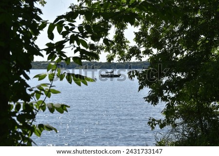 A sail boat calmly floating in a lake surrounded by greenery. I took this picture over the summer.