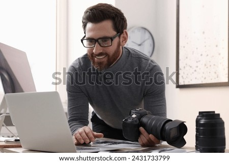 Professional photographer with digital camera using laptop in office